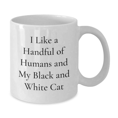 Funny Black and White Cat Gifts from Friends and Family, I Like A Handful Of Humans And My Black And White Cat White Coffee Mug for Graduation, Unique and Humorous Ceramic Mug for Men and Women - Victory Thru Vision